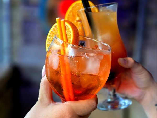 two hands holding two cocktails in front of axe boards for bottomless brunch